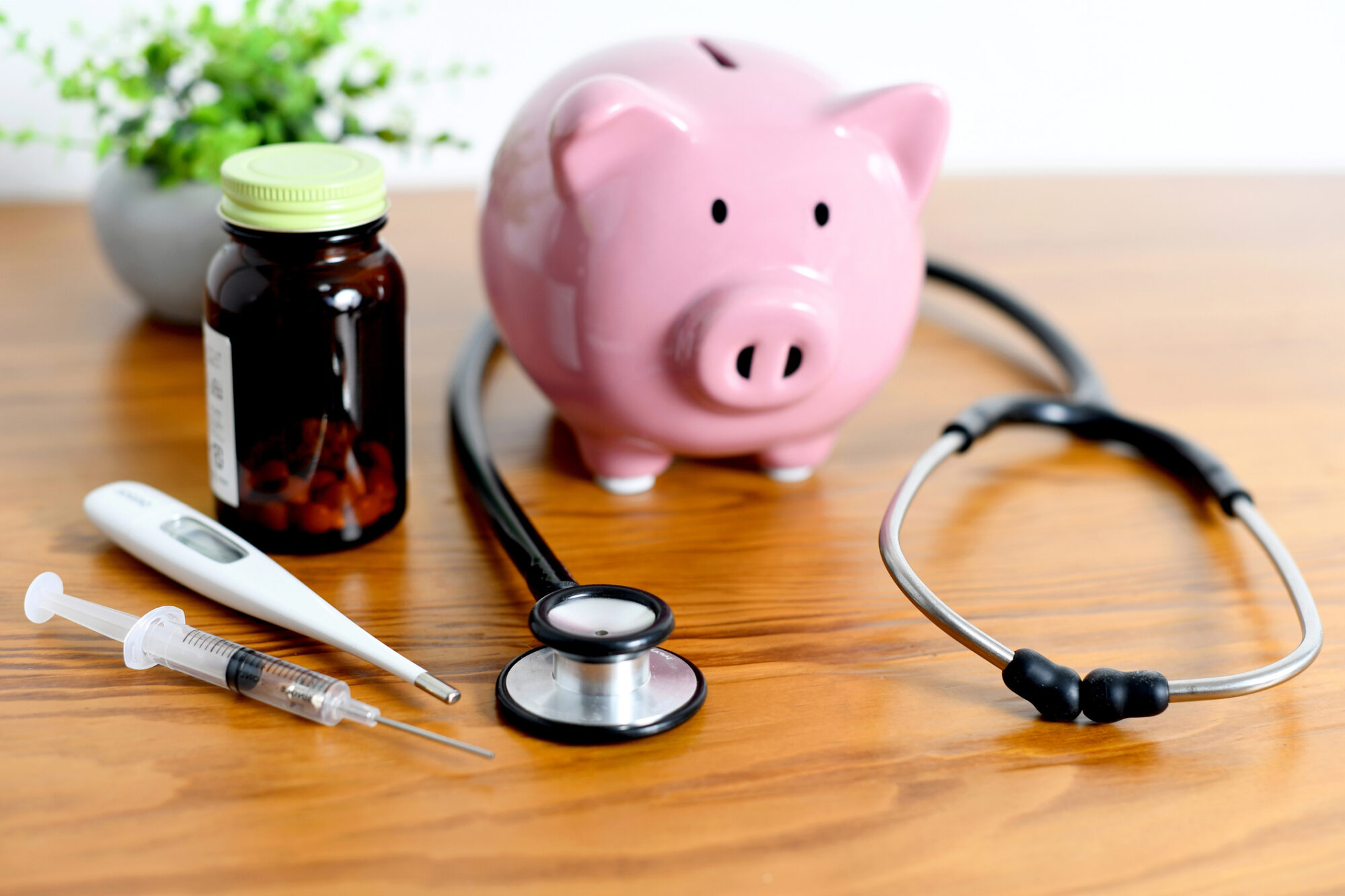 Pig piggy bank and medical equipment such as stethoscope lined up on the desk